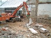 Schwere Baumaschinen brechen das Mauerwerk ein